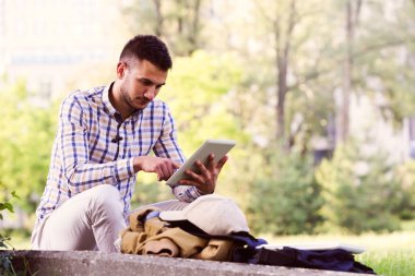 Ekose takım elbiseli, tablet kullanan sıradan bir genç.