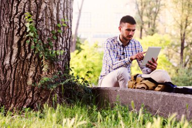 Ekose takım elbiseli, tablet kullanan sıradan bir genç.