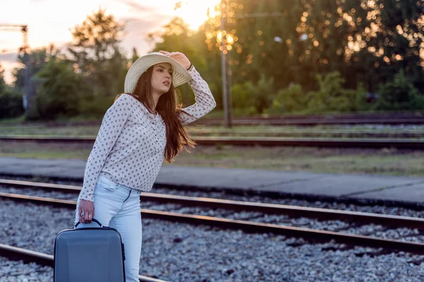 Bagajı olan genç bir kadın gün ışığında yürüyor. Seyahat arkaplanı.