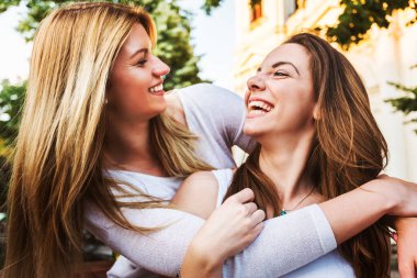 Şehirde gülümseyen kızlar sarılıyor.