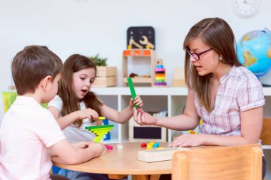 Anaokulu çocukları sınıfta öğretmenle oynuyorlar.