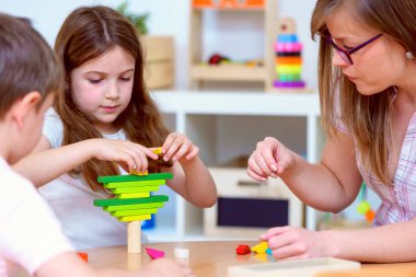 Anaokulu çocukları sınıfta öğretmenle oynuyorlar.