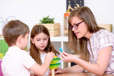 Anaokulu çocukları sınıfta öğretmenle oynuyorlar.