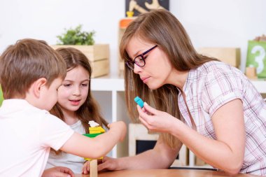 Anaokulu çocukları sınıfta öğretmenle oynuyorlar.