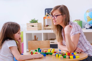  Anne, oyuncaklarla oynayan çocuğuna bakıyor.