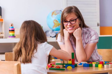  Anne, oyuncaklarla oynayan çocuğuna bakıyor.