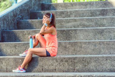 Sportif koşucu kız eğitimden sonra dışarıda dinleniyor müzik dinliyor.