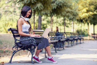 Dizüstü bilgisayar üzerinde kamu parki sohbet oturan güzel genç kadın