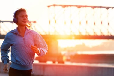 Genç bayan koşucu sabah nehir kenarında koşuyor.