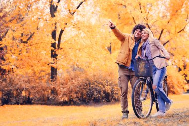 Parkta bisikletle yürüyen neşeli genç çift.