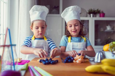 Çocuk şefler mutfakta sağlıklı bir meyve çerezi hazırlıyorlar. Çocuklar için etkinlikler.