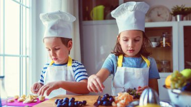 Çocuk şefler mutfakta sağlıklı bir meyve çerezi hazırlıyorlar. Çocuklar için etkinlikler.