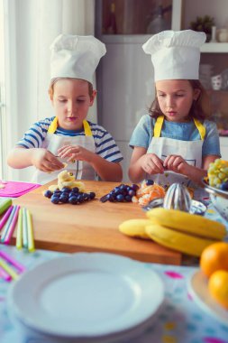 Çocuk şefler mutfakta sağlıklı bir meyve çerezi hazırlıyorlar. Çocuklar için etkinlikler.