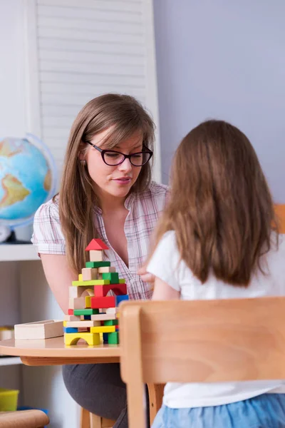 stock image  Mother looking at her child playing with toy building blocks