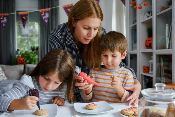 ハロウィンのお祝いのためにクッキーを飾る子供とお母さん — ストック写真