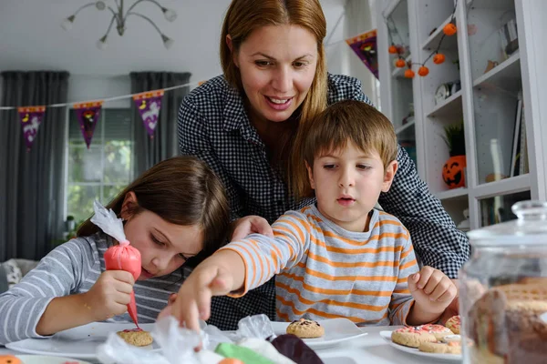 ハロウィンのお祝いのためにクッキーを飾る子供とお母さん — ストック写真