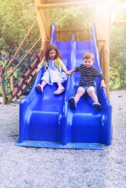 Çocuklar oyun parkında slaytta oynarlar.