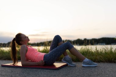 Genç bir kadın plajda yoga egzersizi yapıyor..