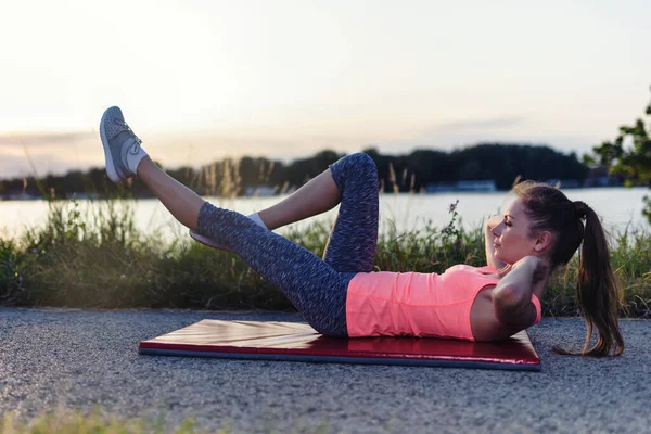 stock image young woman doing yoga exercises on the beach