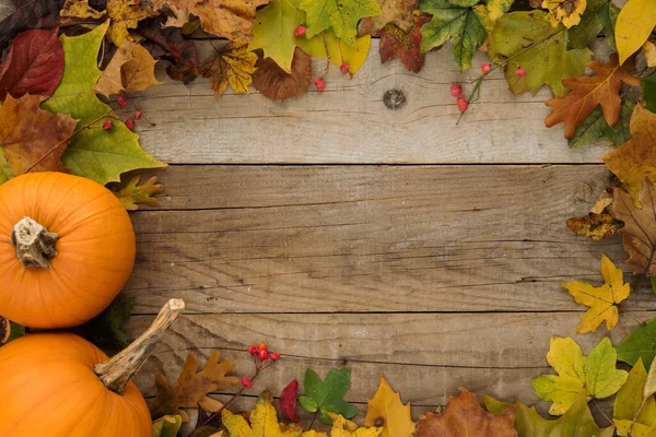 カボチャと木のテーブルの上の葉を持つ秋の背景 — ストック写真