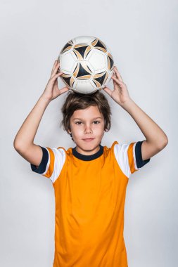 Futbol topu tutan çocuk portreyi yakından tutuyor.