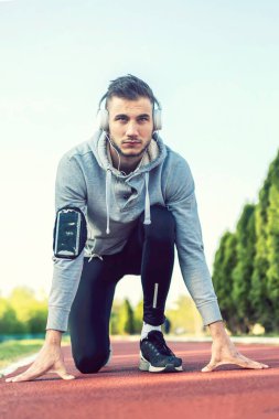 Kulaklıklı yakışıklı bir koşucu köprü altında mola verip müzik dinliyor.