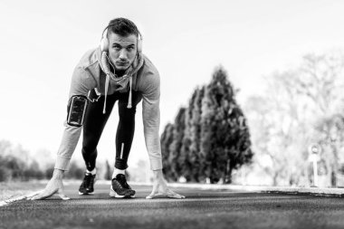 Kulaklıklı yakışıklı bir koşucu köprü altında mola verip müzik dinliyor.