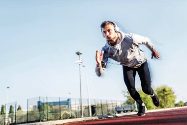 Kulaklıklı yakışıklı bir koşucu köprü altında mola verip müzik dinliyor.