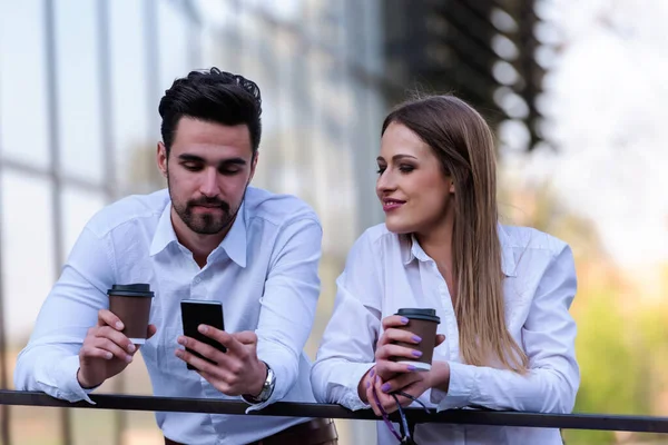 在街上用智能手机笑着做生意的夫妻在喝咖啡休息 — 图库照片