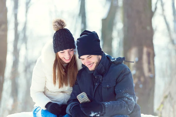 Kar Altında Gülümseyen Genç Bir Çift Akıllı Telefona Bakıyordu — Stok fotoğraf