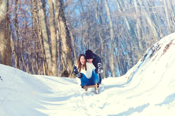 楽しい遊び心のあるカップルの丘を覆われて雪をソリ — ストック写真