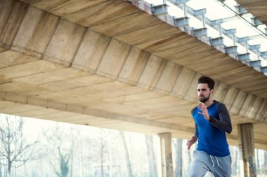 Genç adam şehirde koşuyor.