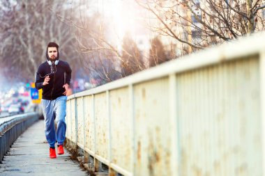 Genç adam şehirde koşuyor.