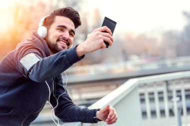 Şehir koşucusu fren yapıyor. Akıllı telefonuyla selfie çekiyor.