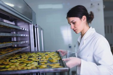 Yiyecek kurutma makinesinin önünde gülümseyen kadın mühendis.