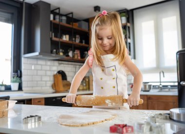 Küçük kız mutfakta hamur hazırlıyor. 