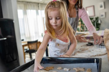 Anne ve kızı evde birlikte yemek pişiriyorlar. 