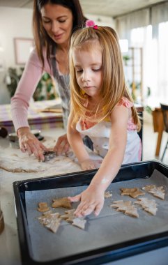 Anne ve kızı evde birlikte yemek pişiriyorlar. 