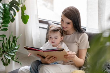 Mutlu anne ve kız evde kitap okuyor.