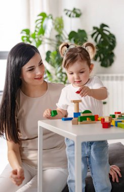 Anne kızıyla tahta bloklar kullanarak oynuyor.