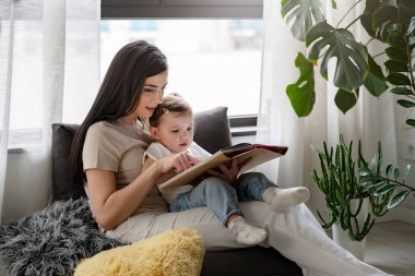 Mutlu anne ve kız evde kitap okuyor.