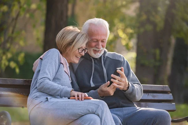 Pareja Ancianos Utilizando Teléfono Móvil Sentado Banco Parque —  Fotos de Stock