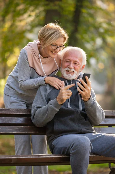 Пожилая Пара Помощью Мобильного Телефона Сидит Скамейке Парке — стоковое фото