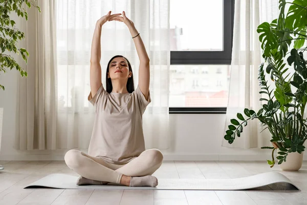 Spor kıyafetli güzel bir kız evde yoga yapıyor. 