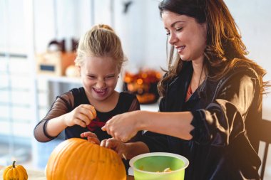 Anne ve kızı Cadılar Bayramı için balkabağı kabağı kabağı kabağı oymaya hazırlanıyor. 