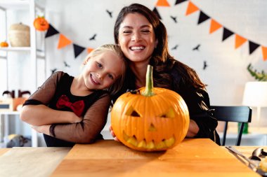 Anne ve kızı Cadılar Bayramı için balkabağı kabağı kabağı kabağı oymaya hazırlanıyor. 