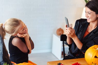 Küçük kızıyla birlikte cadılar bayramına hazırlanan mutlu genç bir kadın.