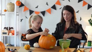 Anne ve kızı Cadılar Bayramı için balkabağı kabağı kabağı kabağı oymaya hazırlanıyor. 