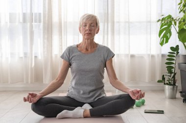 İçeride yoga yapan aktif son sınıf öğrencisi bir kadın.