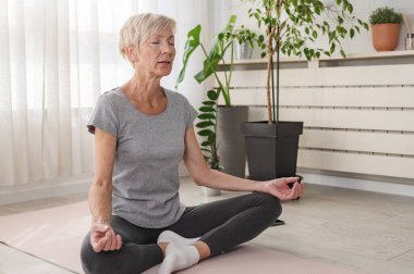 Evde yoga yapan aktif yaşlı bir kadın.